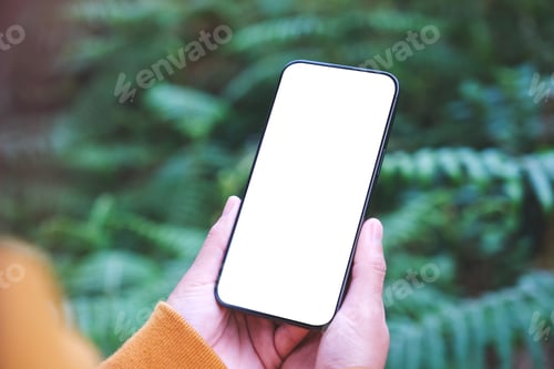 Preview: A woman holding mobile phone with blank white desktop screen in the forest