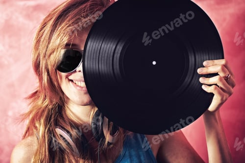 Preview: Fun portrait of a young woman holding a vinyl record up to her face