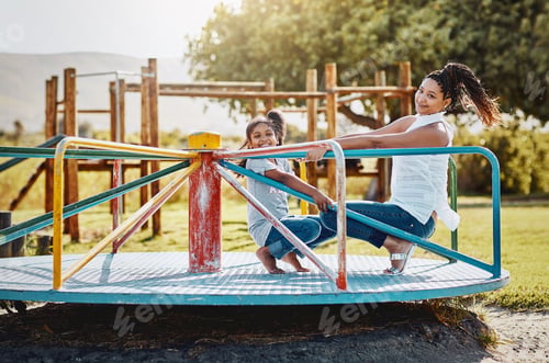 Preview: Portrait of a mother and her daughter playing together on a merry-go-round at the park