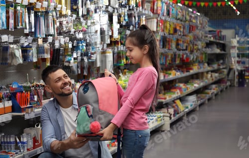 Preview: Little girl with father choosing school stationery in supermarket