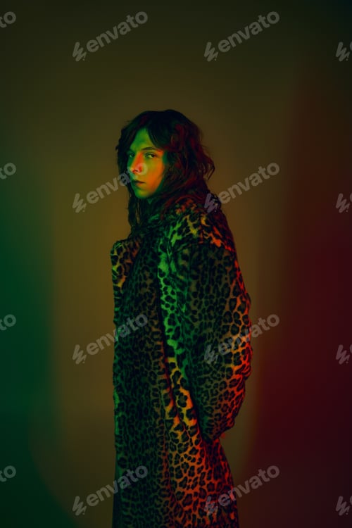 Preview: Handsome young man showcases fashion with a striking leopard print coat and vibrant lighting