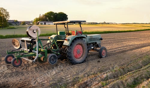 Preview: Tractor with plastic mulch layer on a field at sunset.