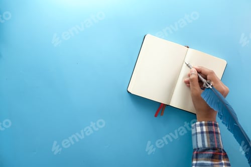 Preview: man hand writing with fountain pen on notepad on blue background