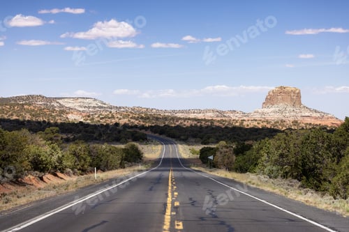 Preview: Scenic Road in the Dry Desert with Red Rocky Mountains in Background.