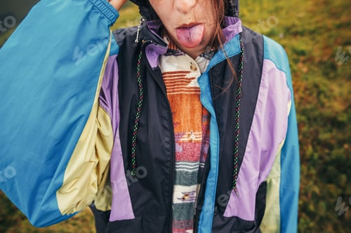 Preview: Girl in colorful raincoat, showing colorful blue tongue from eating blueberries