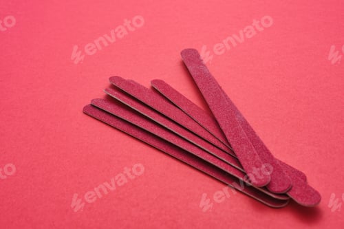Preview: Beautiful shot of red sandpapers made for nail treatment on a light red surface