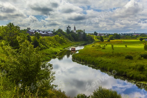 Preview: Aerial shot of a boat sailing on a river in the middle of a grassy field with trees