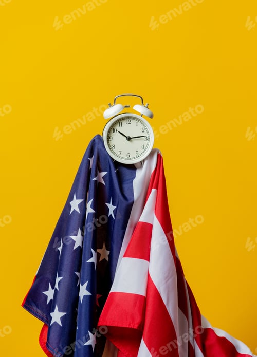 Preview: USA flag and alarm clock on yellow background