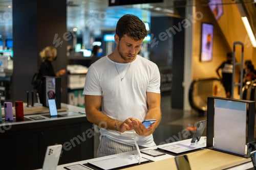 Preview: Focused man choosing smartphone in electronics store