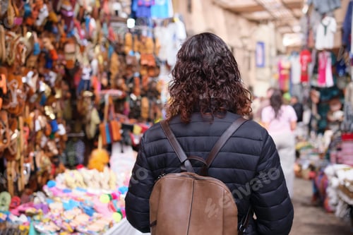 Preview: Woman walking through marrakech souk market with backpack