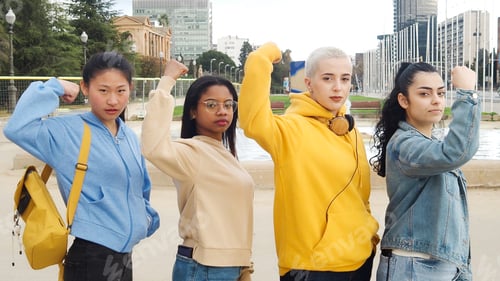 Preview: Group of young empowered women multiethnic looking at camera showing biceps