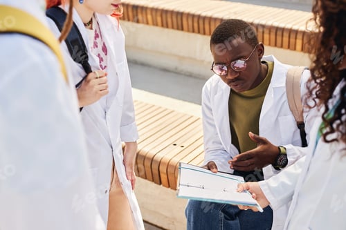 Preview: Student of Medical School Revising Notes in Notebook while Learning Outdoors
