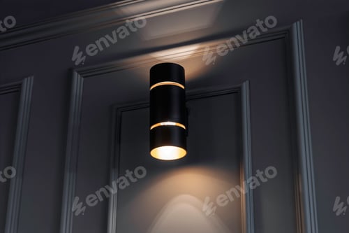 Preview: Modern black wall sconce emits soft light on a textured gray wall, creating a cozy