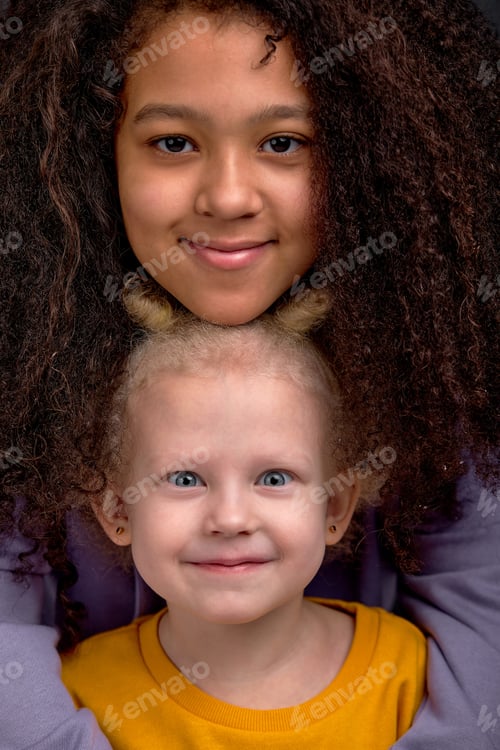 Preview: attractive africamn girl hugs her caucasian little sister