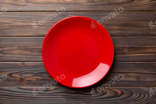 Preview: Top view of empty red plate on wooden background. Empty space for your design