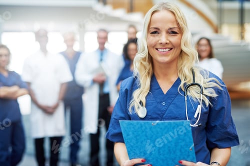 Preview: Cheerful blond medic with documents in hospital