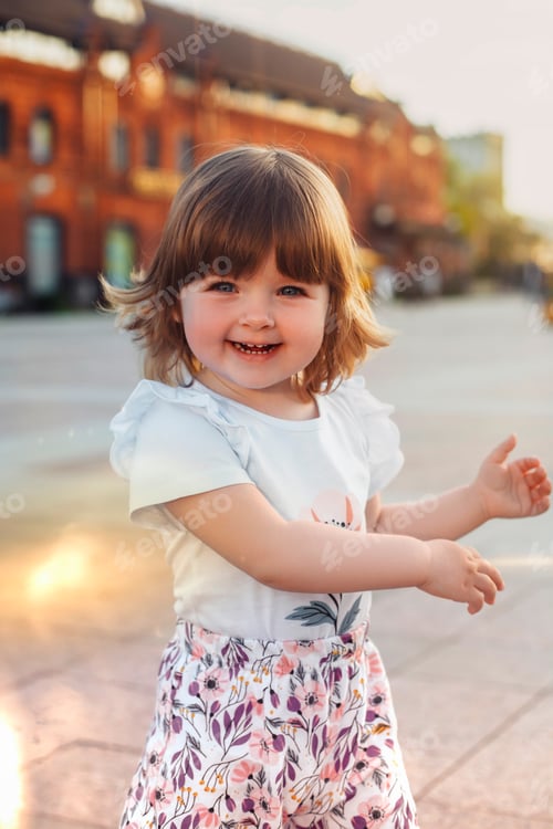 Preview: little girl playing having fun outdoors in the city in summer at sunset