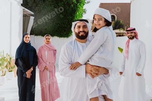 Preview: Emirati family standing together smiling in traditional attire