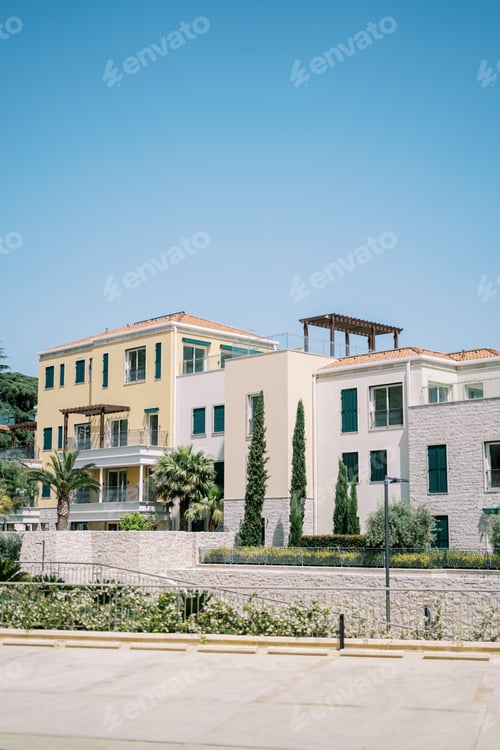 Preview: Colorful hotel complex with terraces and green gardens behind a stone fence