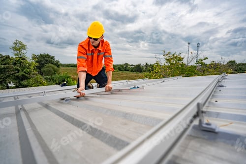Preview: Technician in safety uniform and helmet kneeling on a rooftop