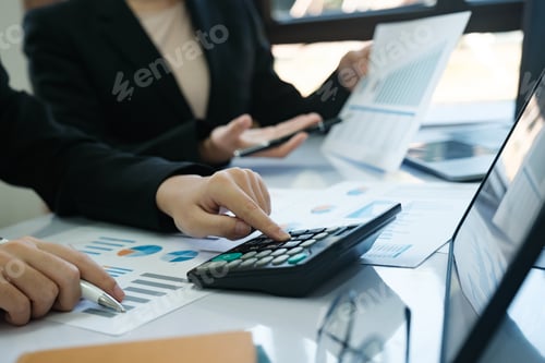 Preview: Two women are working on a spreadsheet, one of them pointing at a calculator