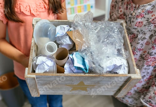 Preview: Two girls in ecology classroom showing box of waste to recycle