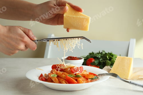 Preview: Woman rubs cheese on pasta with tomato sauce