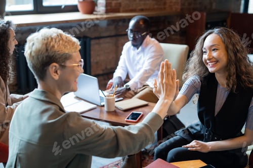 Preview: Happy young manager giving high five to colleague at meeting