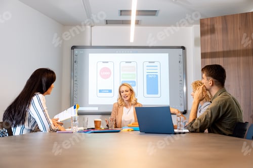 Vista previa: Grupo de empresarios sentados en una sala de reuniones discutiendo el diseño de una aplicación para teléfonos inteligentes.