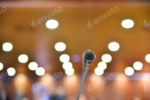 Preview: Microphone on the table of a conference room with unfocused background to communicate news.
