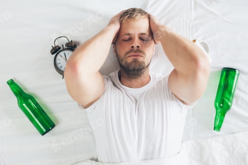 Preview: Young man in bed the morning after night out drinking