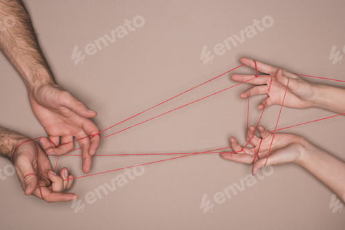 Preview: Top view of man and woman holding red string on beige background