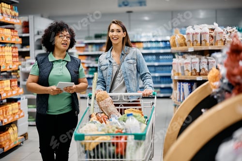 Preview: Happy woman talking to supermarket worker while buying at the store.