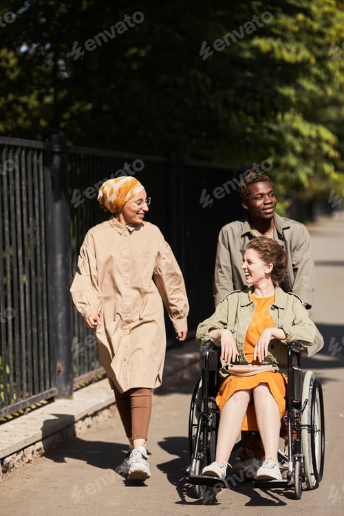 Preview: Pushing disabled woman in wheelchair during stroll