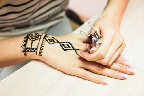 Preview: Drawing process of henna menhdi ornament on woman's hand.