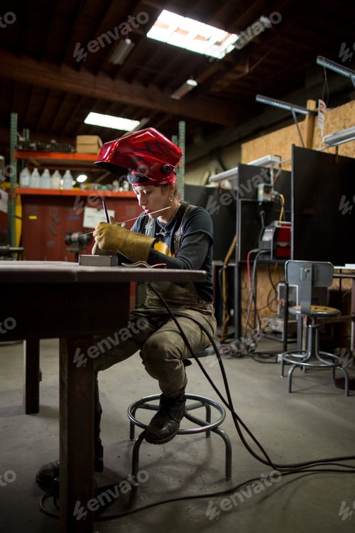 Preview: Female metalsmith preparing metal rods at workshop bench