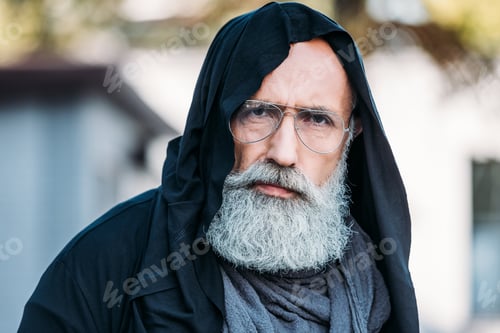 Preview: senior bearded man in fashionable clothing and eyeglasses posing on street