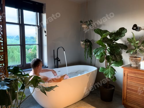 Preview: Middle aged man is taking bath at home or in a hotel. Charming cozy indonesian style. Bathroom view