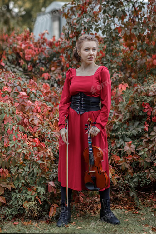 Preview: Young woman in red park playing violin in autumn garden