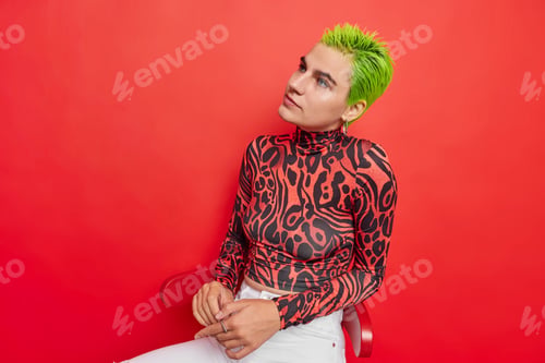 Preview: Pensive green haired woman dressed in turtleneck and white jeans has unusual appearance considers so