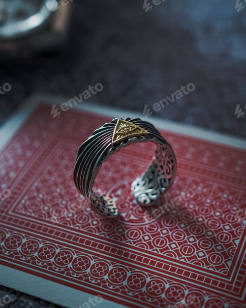 Preview: Vertical shot of a ring with the Eye of Providence symbol on it, placed on a card