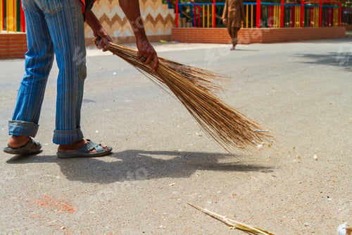 Preview: Man with a hand broom sweeping the street