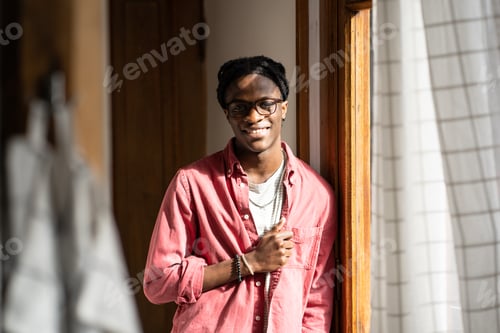 Preview: Cheerful African guy expressing positive emotions, smiling at camera, standing in sunny room