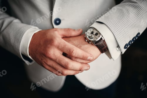 Preview: businessman checking time on his wrist watch, man putting clock on hand,groom getting ready