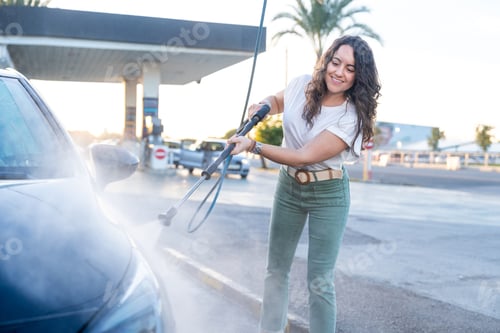 Preview: Young woman washing car with high pressure washer
