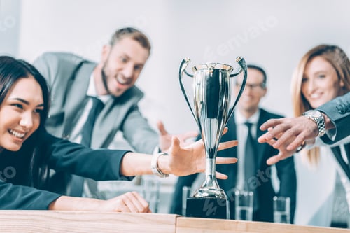 Preview: close-up shot of multiracial businesspeople trying to catch champion cup