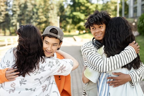 Preview: Teenage Boys Hugging Girlfriends while Couples Greet on Walk in Park