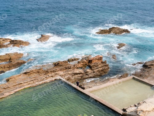 Preview: A serene coastal scene with natural rock pools and a crisp blue ocean.