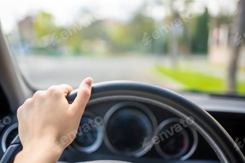 Preview: View of a woman's hand on the steering wheel of a car while driving in the city