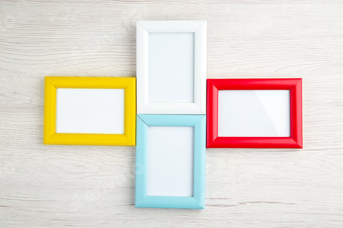 Preview: Overhead view of four empty picture frames in different colors on wooden stripped background